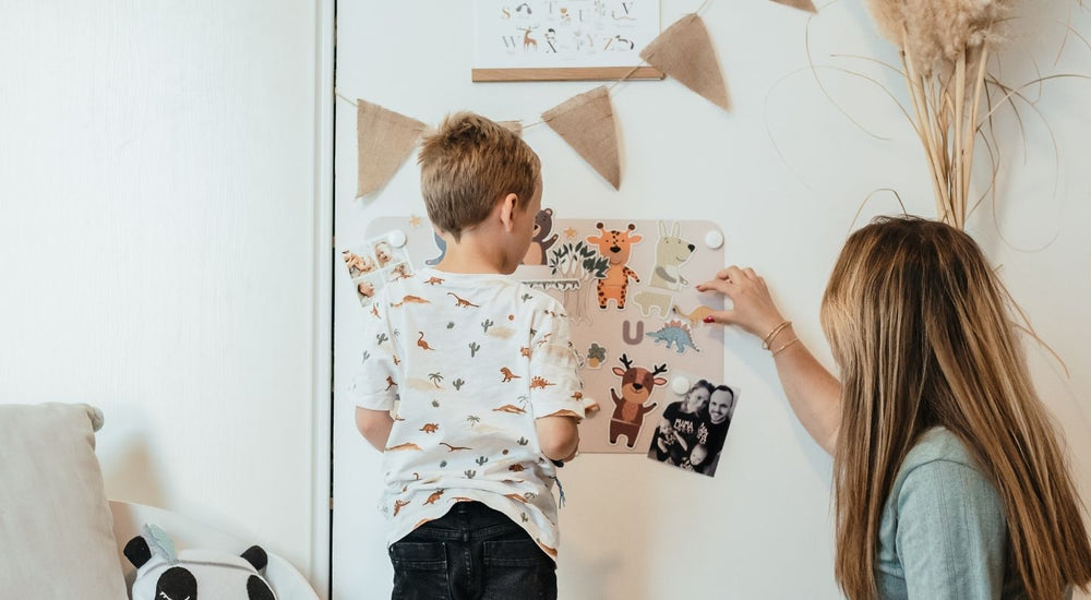 Un enfant et sa mère en train de jouer sur un tableau magnétique