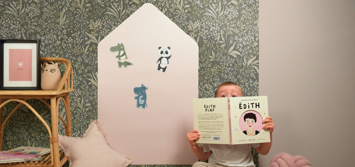 Un enfant dans une chambre avec un livre et un tableau magnétique maison colorée derrière lui