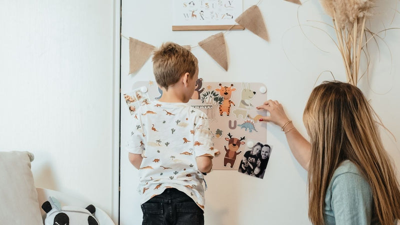 Un enfant et sa mère en train de jouer sur un tableau magnétique