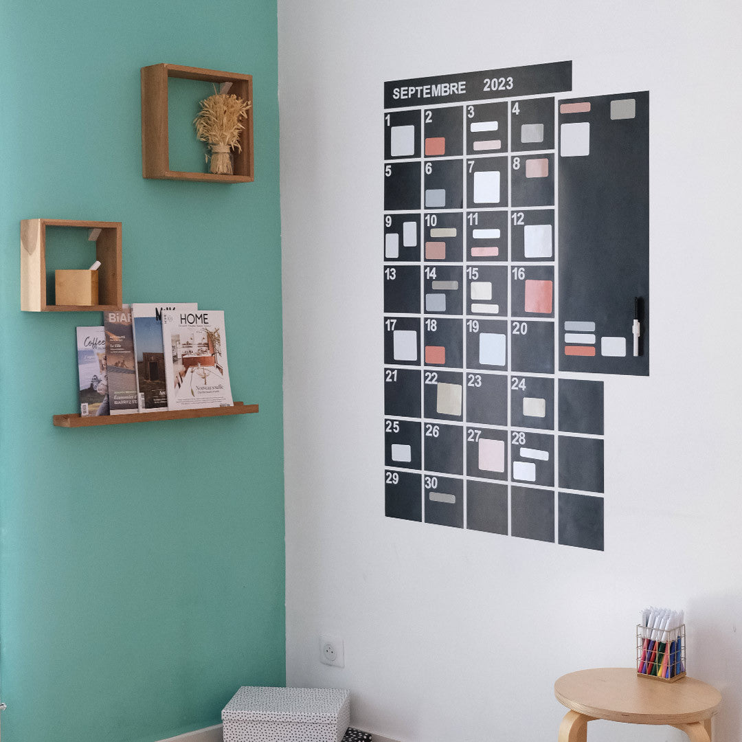 Calendrier mural magnétique mensuel accroché dans un salon décoré