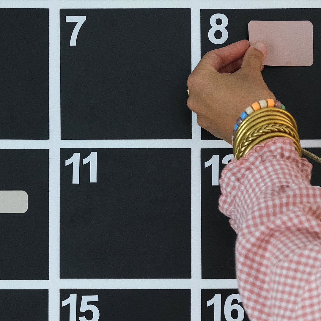 Pose d'un aimant coloré sur une case du calendrier mensuel magnétique
