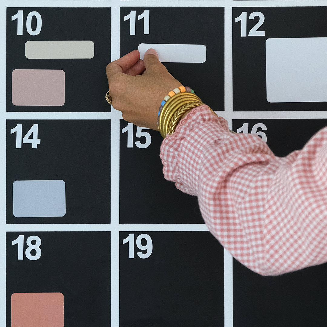 Main plaçant un aimant blanc sur une case numérotée du calendrier magnétique