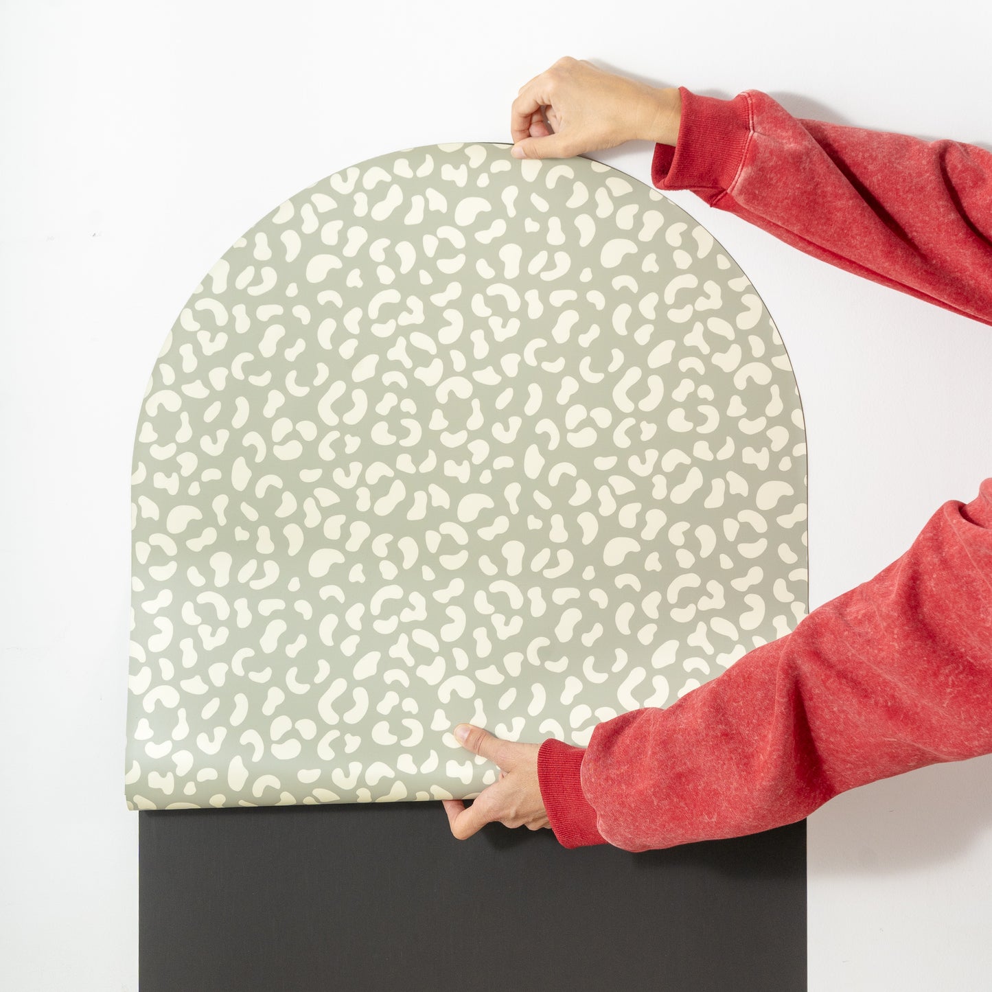 Mains qui positionnent le revêtement imprimé léopard vert sur la base magnétique noire en forme d'arche