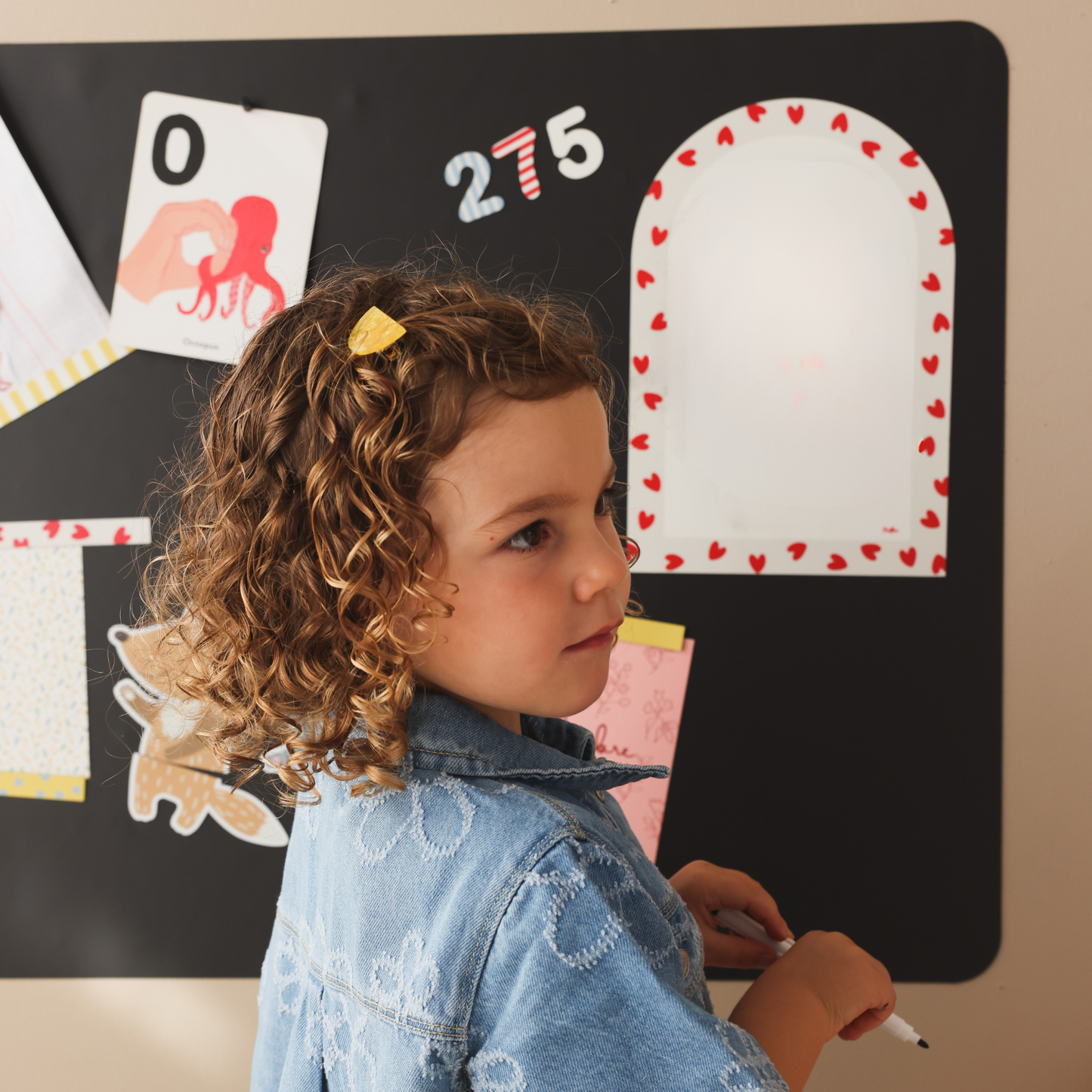 Petite fille devant un tableau magnétique mural rectangle avec chiffres magnétiques primaires et ardoise effaçable à sec petits coeurs rouge