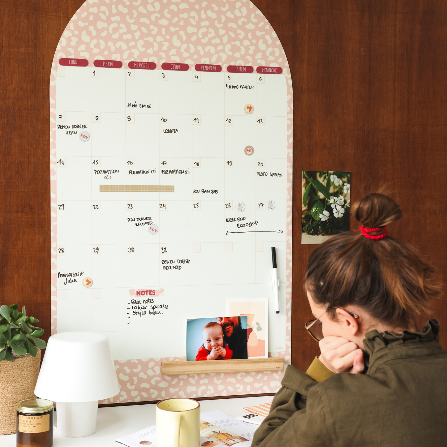 Calendrier magnétique mensuel décoratif posé dans un espace bureau avec accessoires.