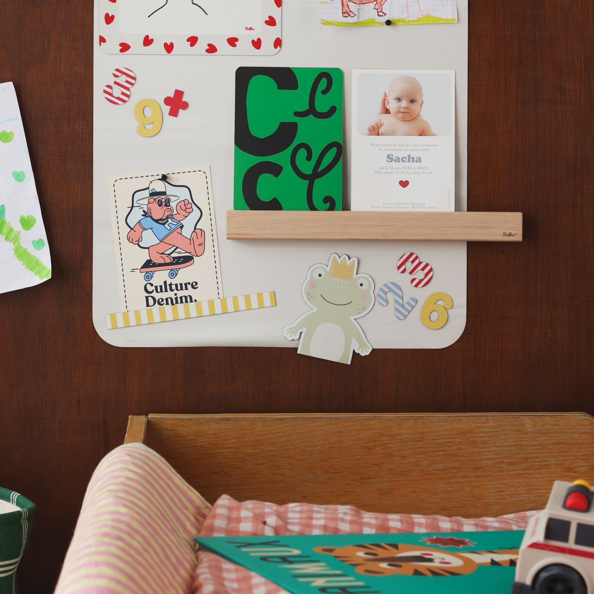 Chiffres magnétiques, étagère en bois et magnet grenouille sur un tableau rectangle beige lin sur un mur en bois essence noyer