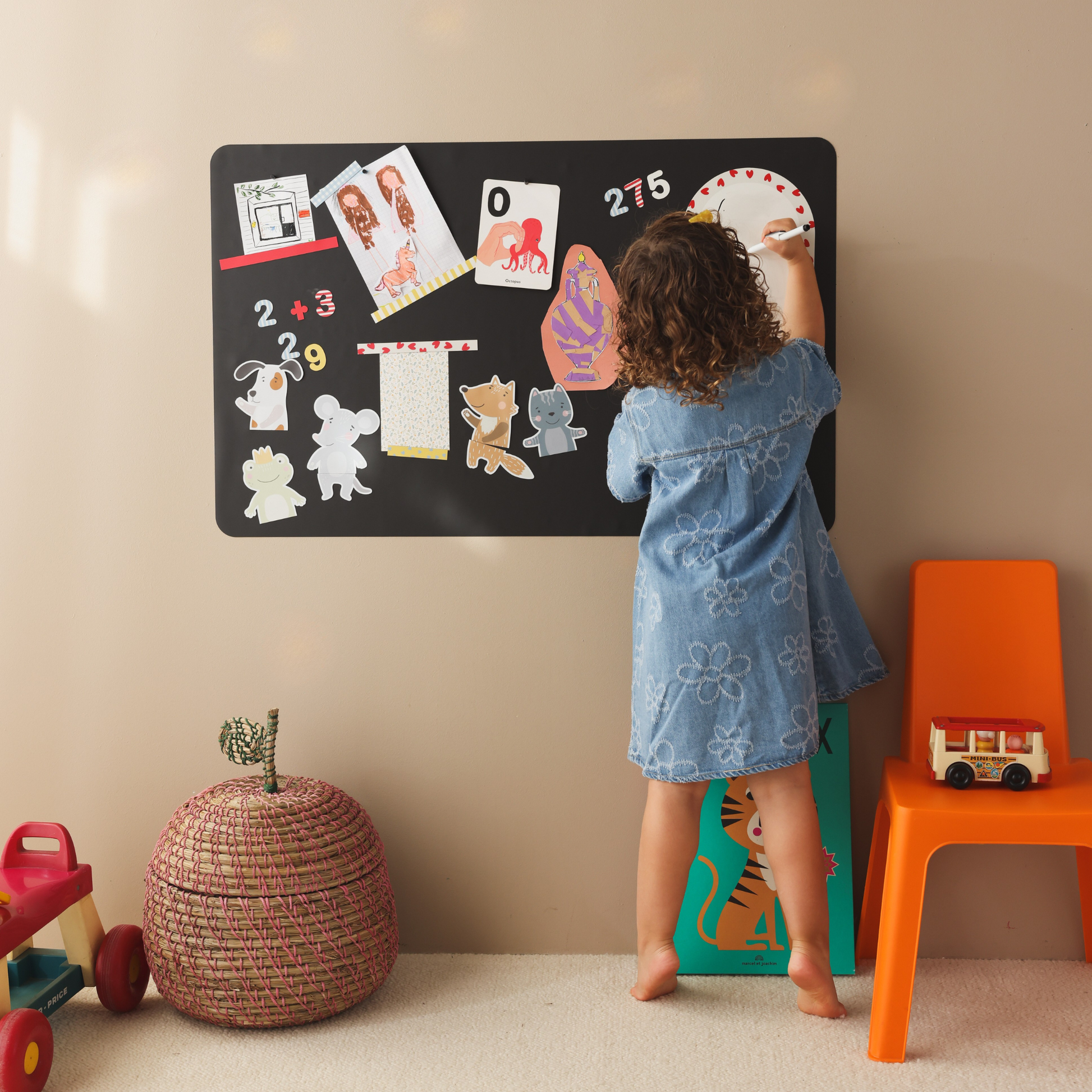 Petite fille jouant sur son tableau magnétique rectangle noir, addition avec des chiffres magnétiques, dessins et cartes