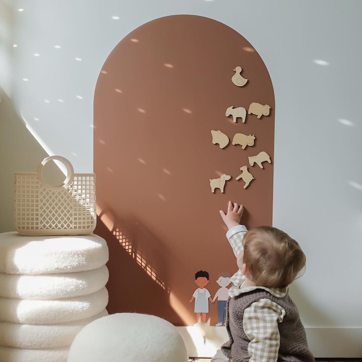 Enfant jouant sur un tableau magnétique en forme d'arche avec des magnets animaux en bois naturel
