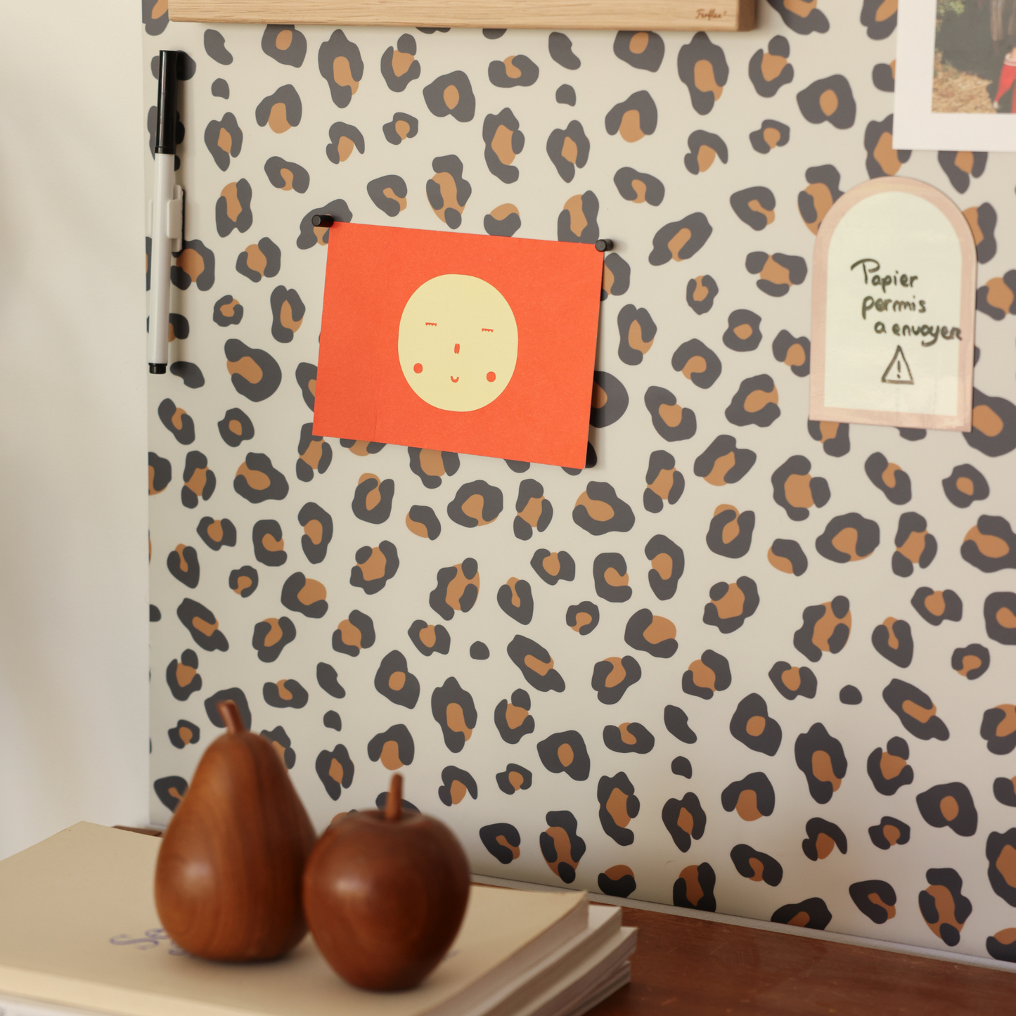 Tableau magnétique léopard avec photos polaroïd, magnets et feutre effaçable à sec au-dessus d'un buffet