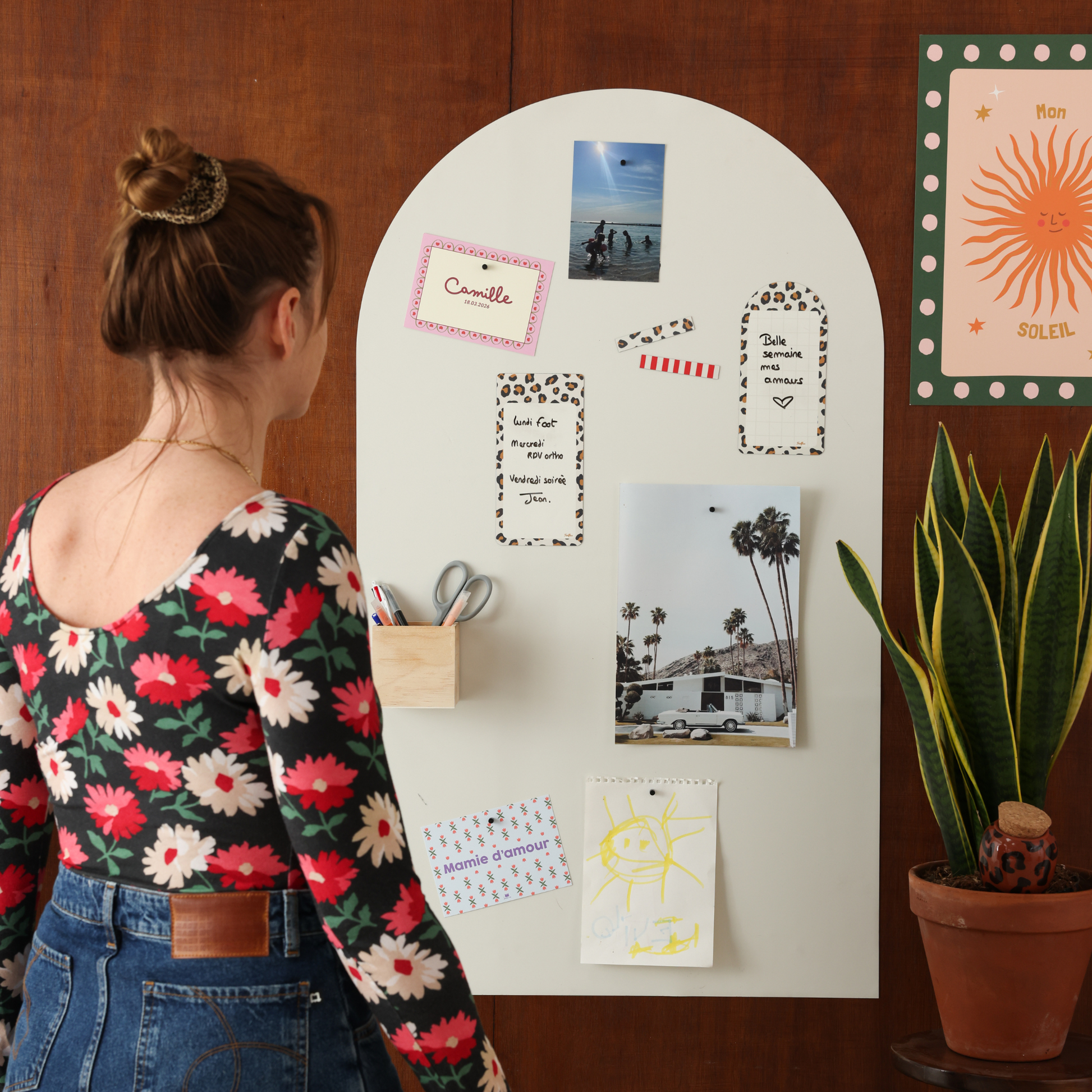 Femme devant un tableau magnétique mural arche beige lin Ferflex® avec faire-part, photos et pense-bêtes