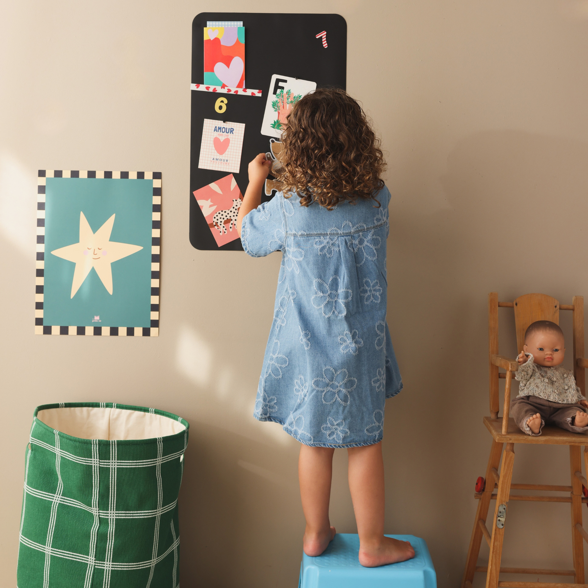 Petite fille jouant avec des magnets souples fabriqués en France sur son tableau magnétique mural