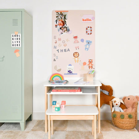 Espace bureau chambre d'enfant avec un tableau magnétique rose et des magnets colorés