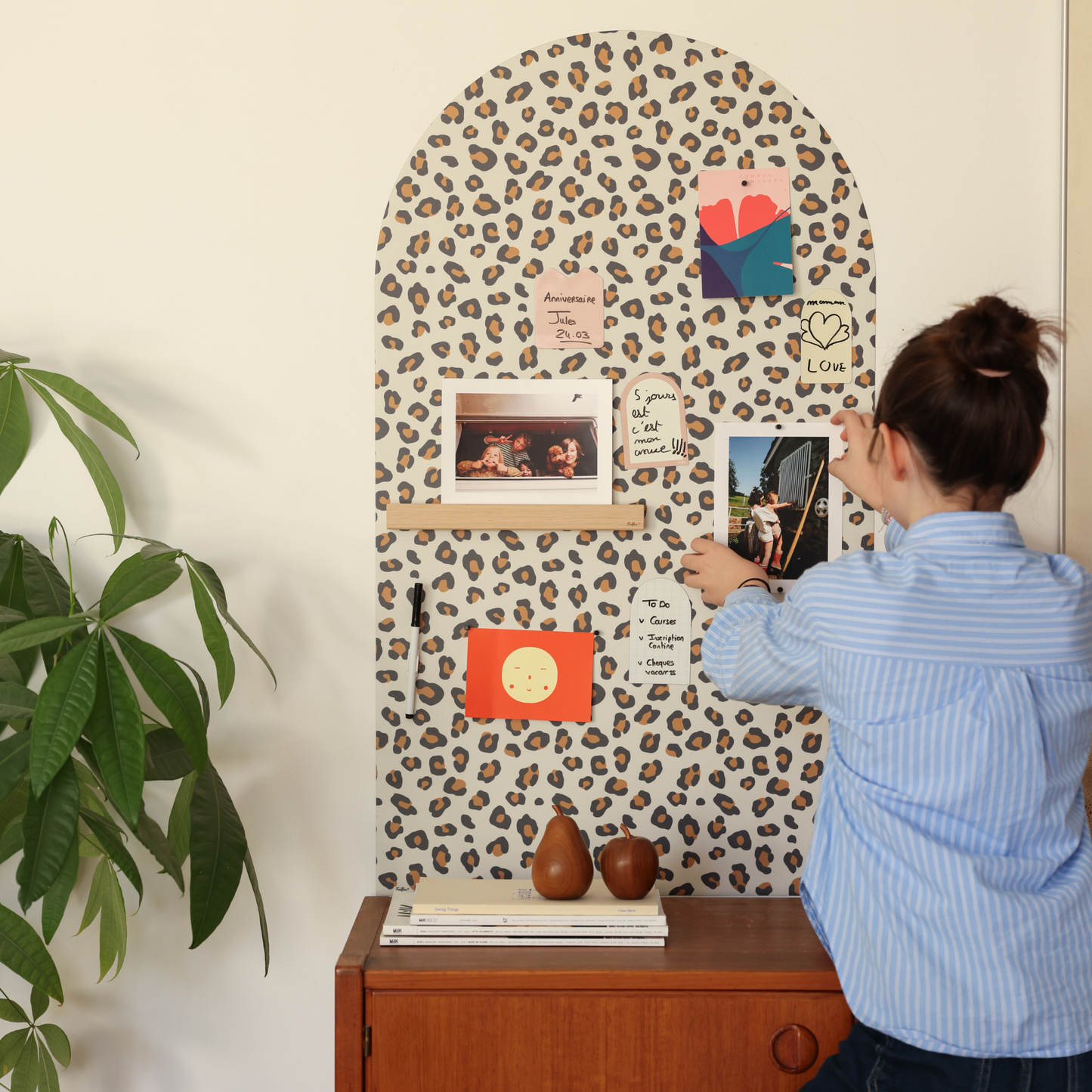 Tableau magnétique mural arche léopard Ferflex® posé sur un buffet en bois, avec photos et pense-bêtes aimantés